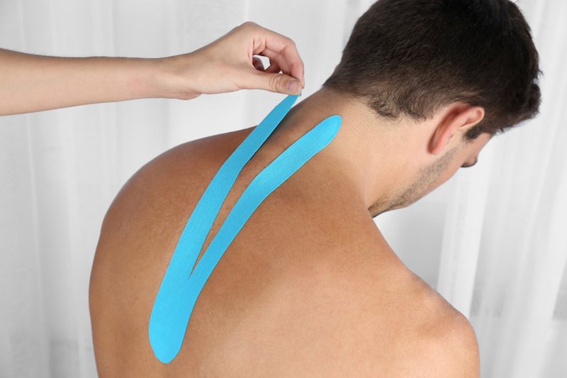 Ein Patient bekommt Kinesio Tapes an den Rücken